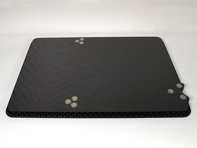 A reflector splashplate is on a white background. There are three sets of three metallic inserts. The panel is constructed of carbon fiber face plates and a carbon core.
