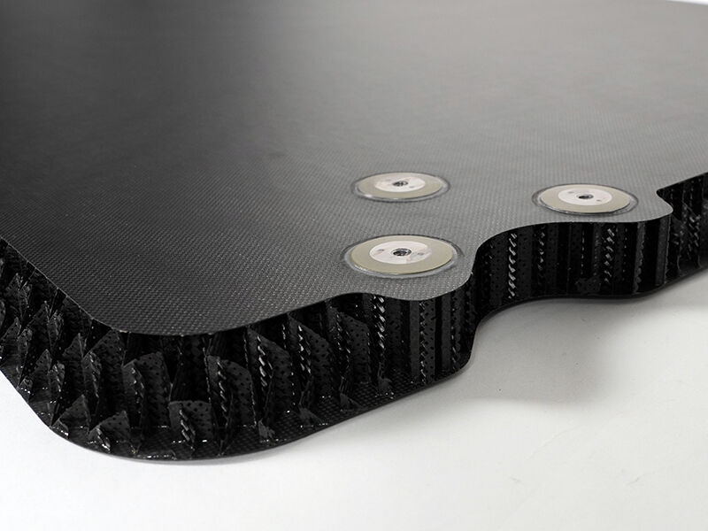 Detail image of a reflector splashplate with a carbon core. The carbon fiber sandwich panel has three metal inserts near the edge.