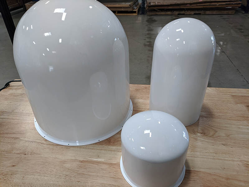 Three white radomes of various sizes on a wood work surface in a warehouse