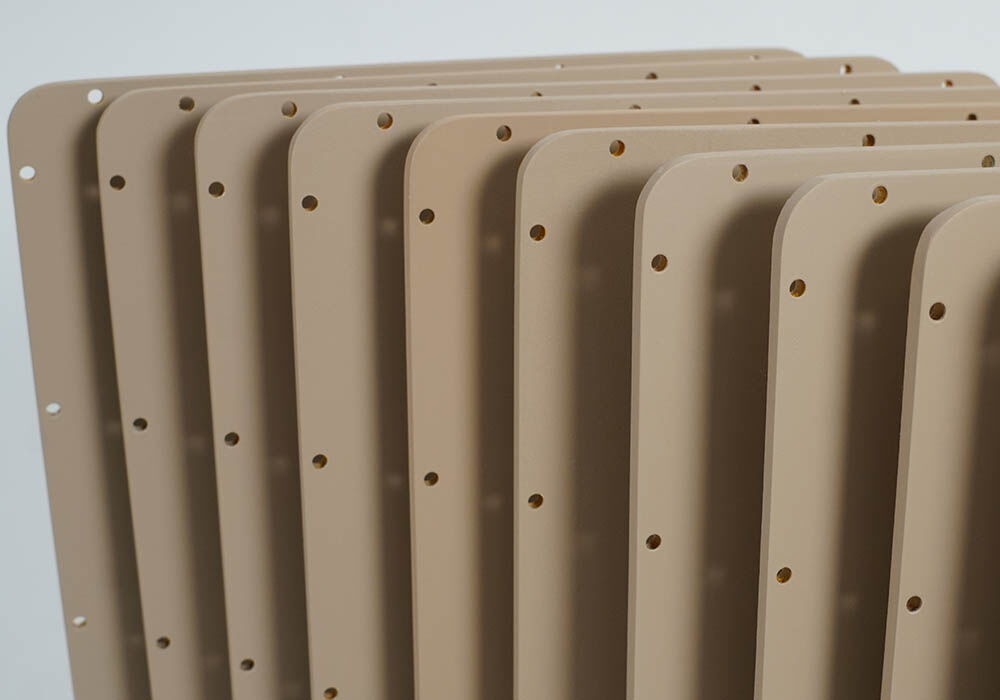 Corner view of a grouping of radome covers that are rectangular in shape with rounded corners, painted a tan color, and machined with attachment holes along each edge. 