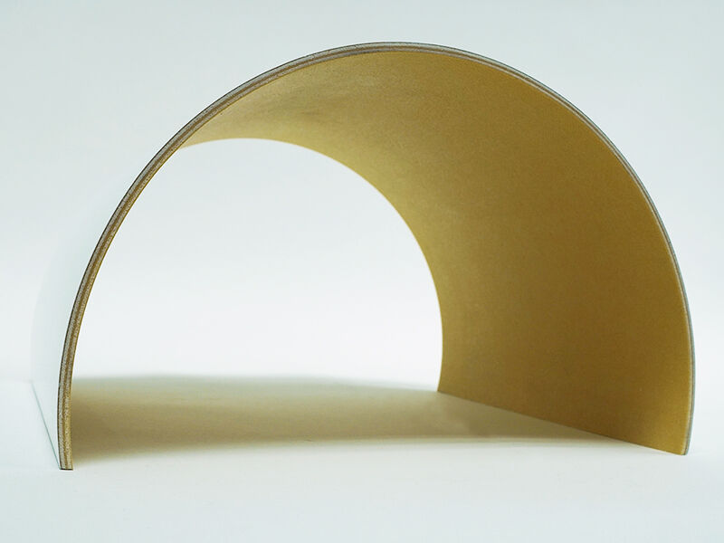 Image of C-sandwich curved panel radome from the front, sitting on a white surface. Interior of the curve is yellowish in color. Outside is painted white. 